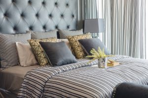 tray of book with vase of plant on bed in luxury black bedroom at home