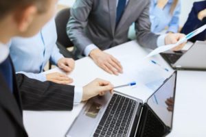 businessmen discussing over a laptop and papers Image