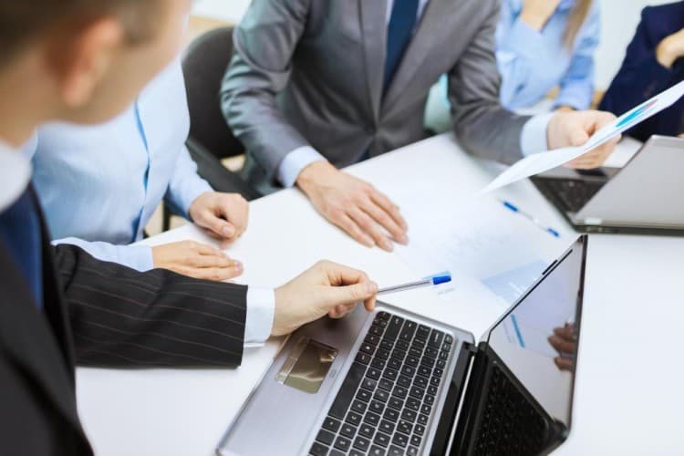 businessmen discussing over a laptop and papers Image