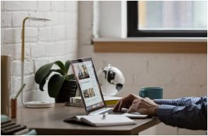 A man is working on his laptop for small business SEO services with a cup of coffee nearby